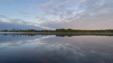 Clouds reflecting on a still lake in the early morning light Vidéo 219227756