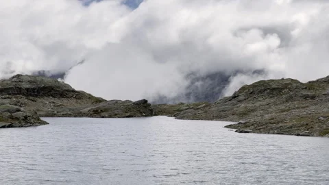 Clouds rising over wind rippled alpine lake - Static mountain view 스톡 동영상 328406897