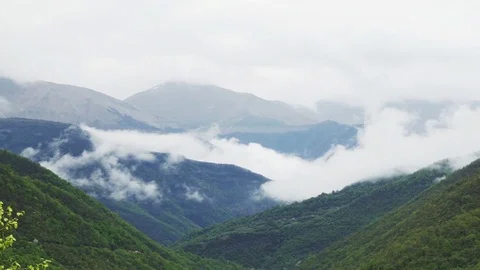 Clouds roiling and flowing over peaks of Mountain Range Stock Footage 77527214