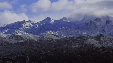 Clouds rolling across snowy mountain peaks in Spain. Video stock 337652991