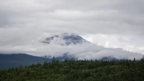 Clouds rolling around a mountain peak above forest in Alaska timelapse Stock-Footage 347818920