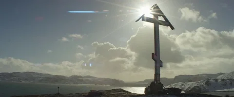 Clouds rolling over the cross near the lake and snow covered mountains 库存影片 74675319
