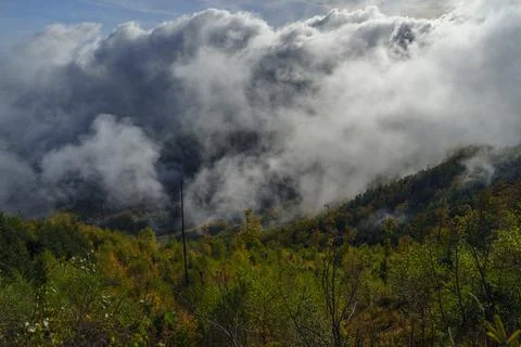Clouds rolling over green mountain slope in autumn Stock Photos