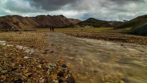 Clouds rolling over mountains and geothermal river with multicolored pebbles Stock Footage 73011767