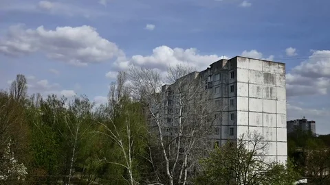 Clouds run over a blue sky over an old high-rise building in a poor getto area Stock Footage 129110307