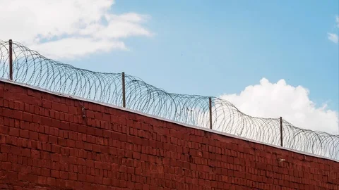 Clouds running free outside prison wall with barbed wire in timelapse Stock Footage 108872363