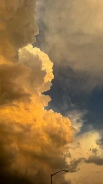 Clouds shift colors in the sky over a city at sunset with a light pole visi.. Stock Photos