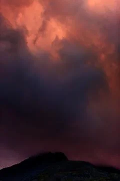 Clouds in the sky above the mountains lit by the sun at sunset. Stock Photos
