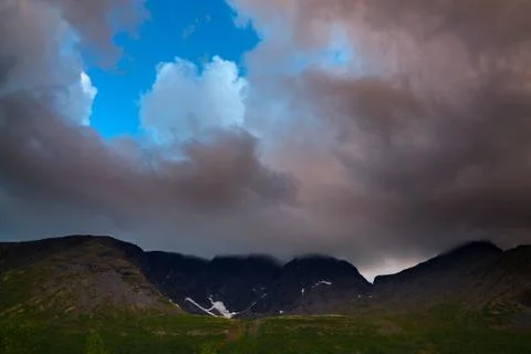 Clouds in the sky above the mountains lit by the sun at sunset. Stock Photos