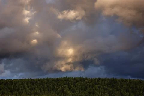 Clouds in the sky above the mountains lit by the sun at sunset. Stock Photos