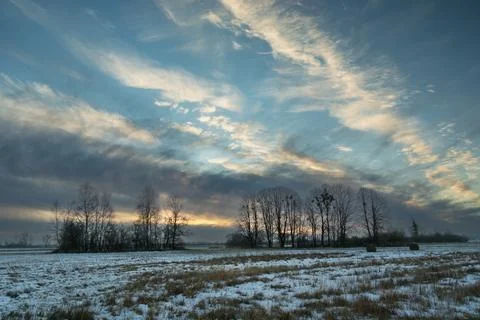Clouds in the sky during sunset over a meadow with trees, winter December Stock Photos