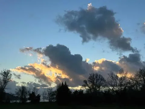 Clouds in the sky during sunset with trees in the foreground Stock Photos