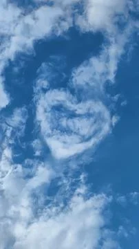 Clouds in the sky form a heart shape during a bright day, symbolizing love .. Stock Photos