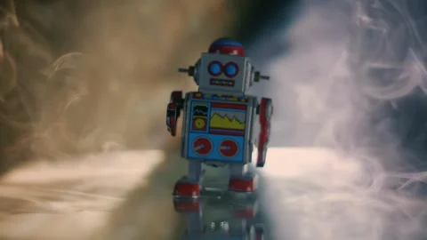 In clouds of smoke wind-up robot walks on a glass surface in the color rays Stock Footage 313155090