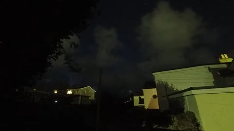 Clouds speeding across night sky time lapse transition illuminated houses Stock Footage 325743203