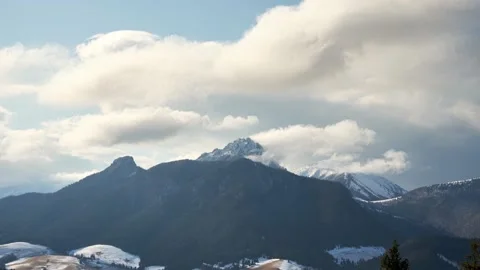 Clouds spill over the mountain alpine peaks. April's changeable weather Stock-Footage 185564841