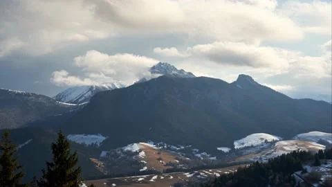 Clouds spill over the mountain alpine peaks. April's changeable weather Stock Footage 185571281