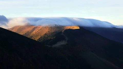 Clouds spill over the mountain ridge. Autumn in the mountains in a national park Stock Footage 254546630