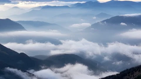 Clouds spill over the tops of the hills in the light of the rising sun, Mystical Stock Footage 169599718