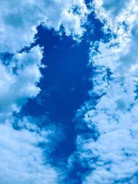 Clouds spread across the sky creating shapes and patterns over a bright blue  Stock Photos