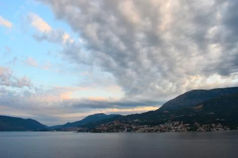 Clouds stretch over a bay, which is surrounded by hills and mountains. Stock Photos