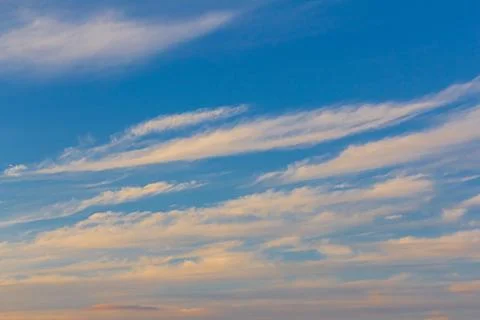 Clouds stretched across the blue sky in the rays of yellow-gold from the sett Photos