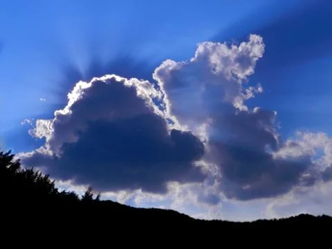 Clouds, sun and a mountain Stock Photos