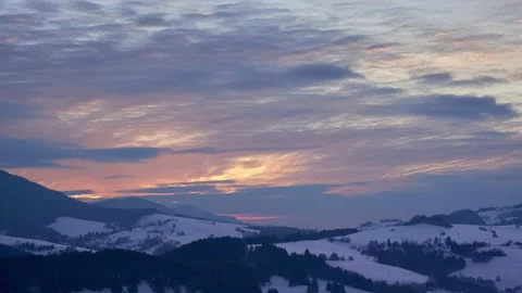 Clouds at sunset over a snowy hilly rural landscape. Orange coloured clouds Stock Footage 233445508
