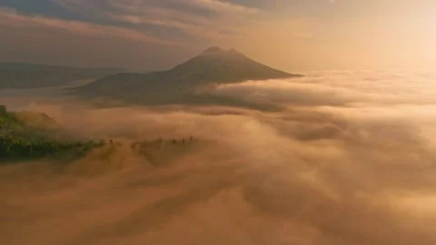 Clouds surrounding mountain at sunset, creating a beautiful afterglow in the sky Stock Footage 265447806
