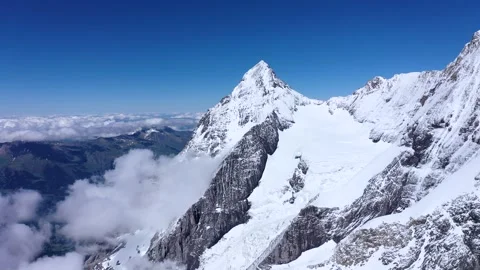 Clouds surrounding the peaks of a tall mountain Stock Footage 247796686