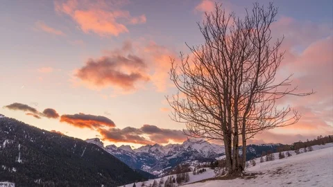 Clouds through a tree during a winter sunset and dolomites in the background Stock Footage 125565218