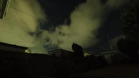 Clouds time lapse passing over garden flashing from home lights Stock Footage 325743241