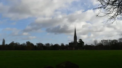 Clouds Time Lapse Winter Morning Church in Far Distance Green Grass Foreground Stock Footage 168220625