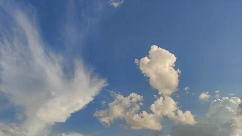 Clouds of various shapes and sizes drift across a bright blue sky Stock Photos