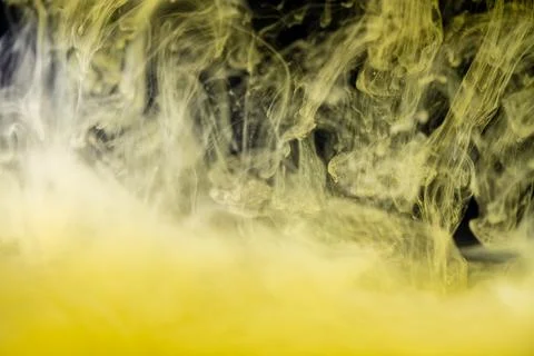 Clouds of yellow smoke on a black background, clouds of paint in water, aquar Foto stock