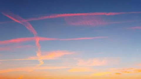 Cloudscape with airplane trails at sunset Stock Photos