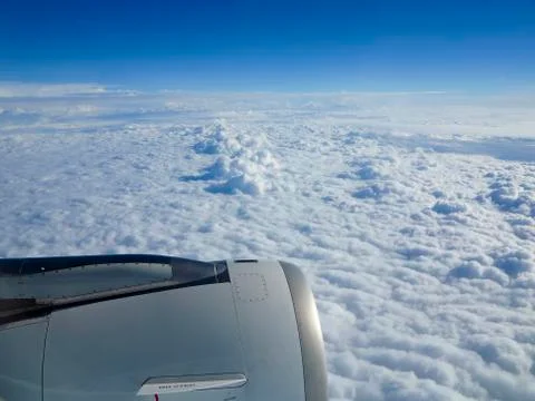 Cloudscape and engine seen through an airplane window Stock Photos
