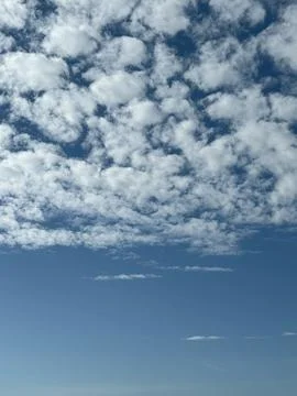 Cloudscape background with scattered white clouds against a clear blue sky 写真素材