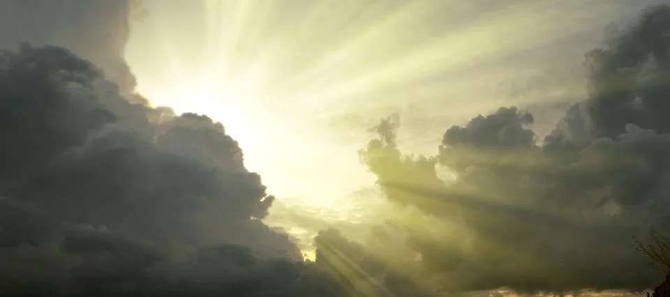 Cloudscape image of dark stormy clouds in blue sky with sun beam. The rays of Stock Photos