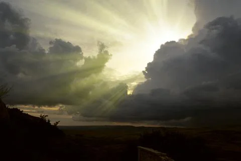 Cloudscape image of dark stormy clouds in blue sky with sun beam. The rays of Stock Photos