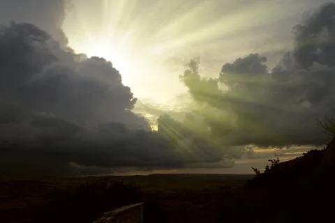 Cloudscape image of dark stormy clouds in blue sky with sun beam. The rays of Stock Photos