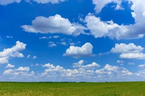 Cloudscape over green field Stock Photos