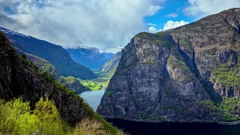 Cloudscape over the rugged mountains and cliffs plunging into a fjord or Stock Footage 203879420