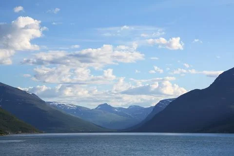 Cloudscape over snowy mountain range and lake in norway Stock Photos