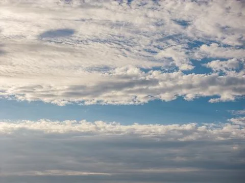 Cloudscape with two bands of textured white altocumulus clouds separated by a Photos