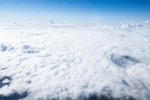 Cloudscape viewed from above during daytime flight shows a vast expanse of Stock Photos