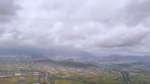 Cloudy aerial view of vast rice fields and distant city skyline in Busan, Stock Footage 286232550