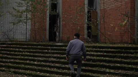 Cloudy autumn day, a guy in a black hat climbs the grass-covered steps and Stock Footage 287148924