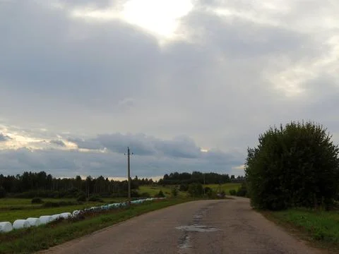 Cloudy autumn sky with gray clouds and a yellow gap, under it-fields and coun Stock Photos