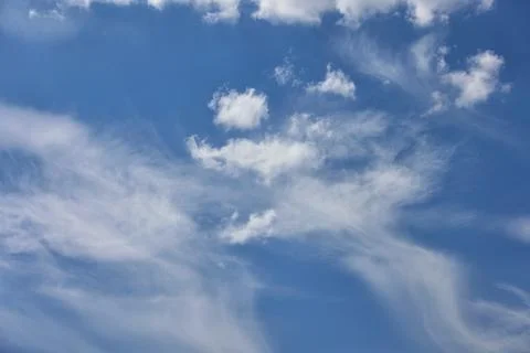 Cloudy blue sky background with white swirling clouds. Stock Photos